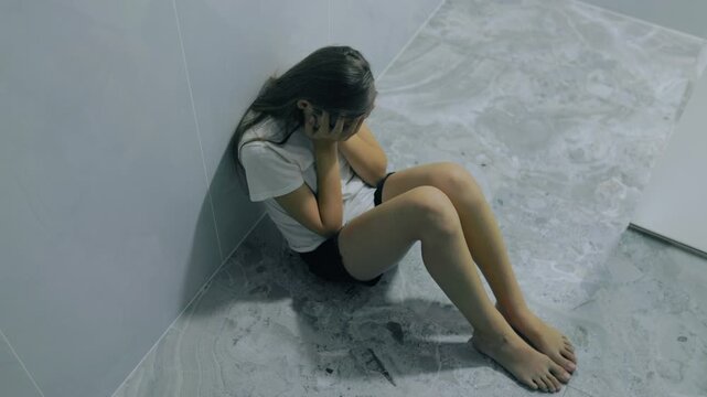 Anxious generation z teenager sitting on floor hiding face crying.