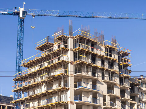High-rise residential building under construction with a tower crane. Concept of urban development, real estate, and the housing industry.