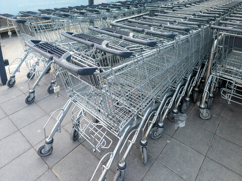 Rows of Metal Shopping Carts Lined Up Outside Supermarket Entrance, Retail Store Trolleys