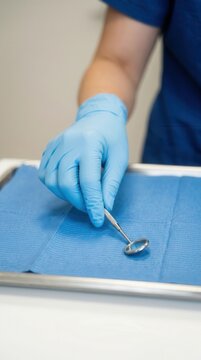 Hygienist Using a Sterile Mirror Instrument on a Clinical Tray for Precise Oral Healthcare and Routine Patient Treatment Procedures