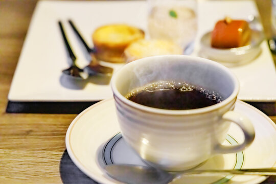 温かいホットコーヒーと奥に見えるスイーツプレート