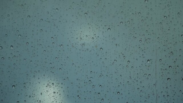 Raindrops on Glass Surface with Blurred Blue Background on a Wet Day