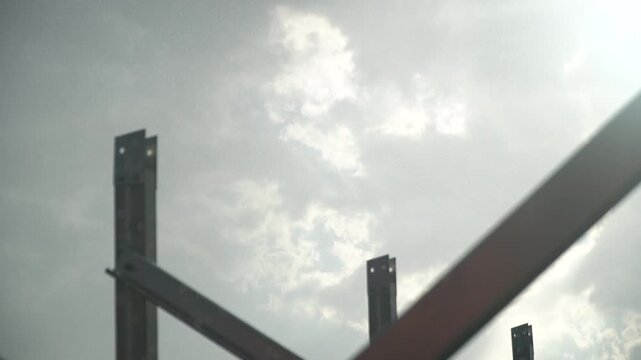 Metal Framework of an Unfinished Building Against a Bright, Cloudy Sky