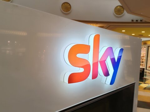 Rome, Italy - June 15, 2025, detail of a luminous Sky sign, the pay-TV platform offering satellite and streaming content, owned by Comcast's Sky Group, inside a shopping mall.