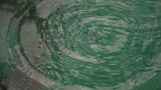 Raindrops Falling on a Green Water Surface Creating Ripples and Bubbles