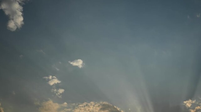 Timelapse of moving late day clouds and strong sun rays projecting from the bottom of the frame
