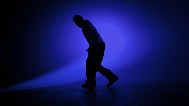 Hip hop dancer performing a freestyle pose in blue studio