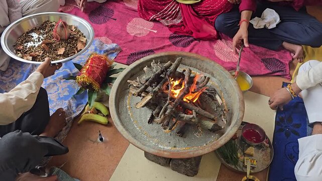 The havan kund fire burns bright during a hindu ritual ceremony as participants make traditional offerings
