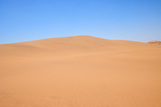 Eine einzelne hohe Sandd&uuml;ne steht unter klarem Himmel in der W&uuml;ste bei Swakopmund in der Region Erongo, Namibia.