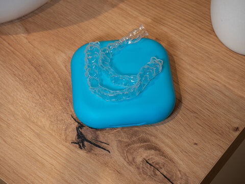 clear plastic dental aligners on blue case wooden surface