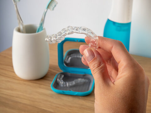 hand holding clear dental aligners retainer bathroom background