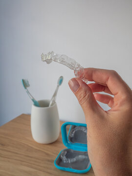hand holding clear dental aligners retainer bathroom background