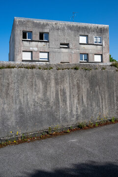 Verwittertes Wohngeb&auml;ude hinter einer hohen Betonmauer in Brest