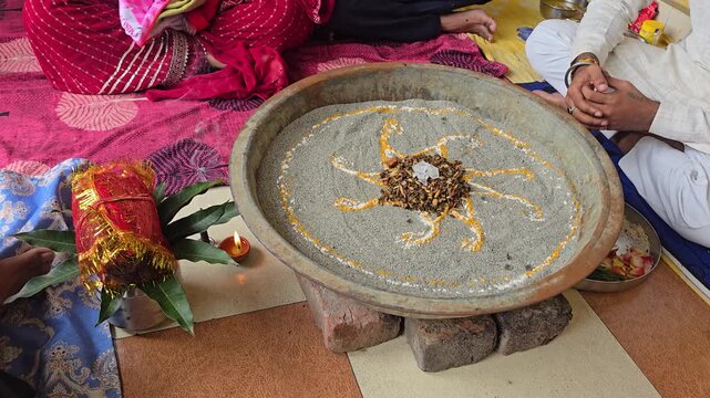 Close up view of a ritual basin decorated with sand patterns and wood offerings during a spiritual ceremony