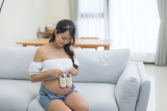 Pregnant woman holding small baby shoes