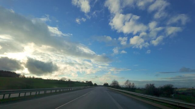 POV Driving on a Scenic Countryside Highway Under a Dramatic Blue Sky with Clouds