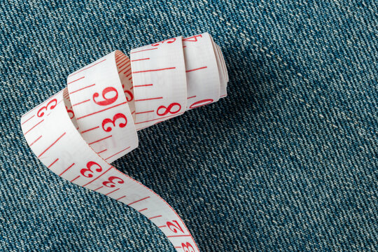 Tape measure on denim fabric displaying size and tailoring