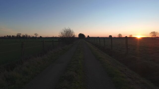 Cinematic POV Shot Walking Down a Rural Dirt Road into a Golden Sunrise