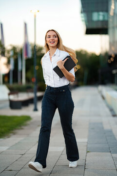 Young business professional smiling while walking outdoors with a digital tablet