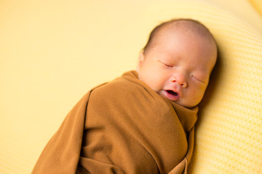 Sleeping newborn baby wrapped in brown cloth in taiwan
