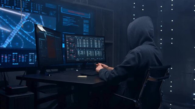 Hacker working on computer in dark room. Cyber criminal coding with digital data screens.