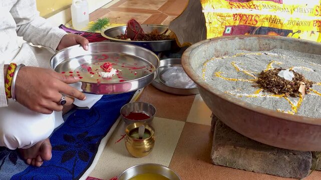 Performing hindu religious ritual with sacred offerings a person preparing items on a metal plate