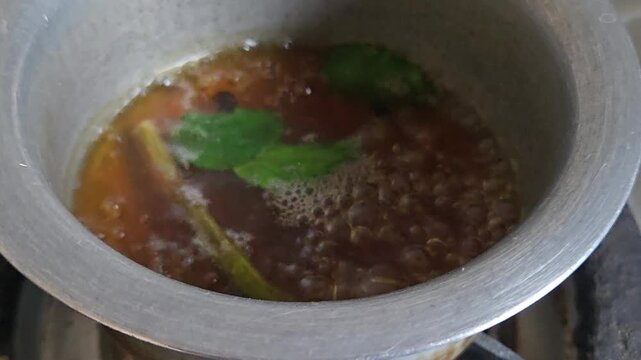 This giloy stem, tulsi, and black pepper kadha boils on a hot stove flame. Sweetened with jaggery, it boosts immunity, fights severe respiratory infections, purifies blood, and reduces body fevers.