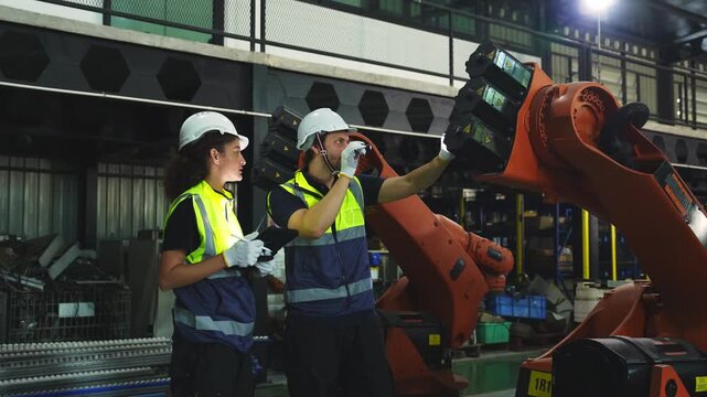 Industrial engineer inspecting a robotic arm machine in an automated manufacturing factory, robotics, automation, smart manufacturing, machine maintenance, quality control and Industry 4.0 technology.
