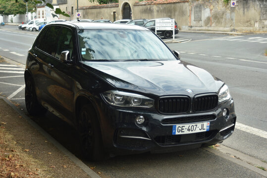 St-Amand Montrond - France - 30 July 2026 - Side front view of a dark gray BMW X5 F15 luxury SUV parked along a quiet tree-lined road