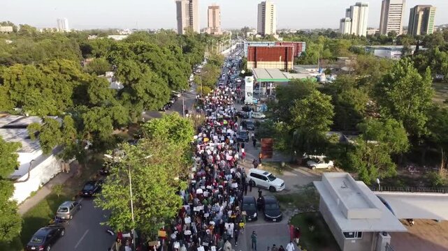 Large crowd marching on city street. Aerial view of people protesting in urban area.
