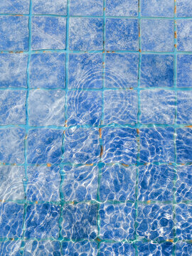 Water park pool surface with bright blue rippling water, aerial view of crystal clear aquatic leisure facility