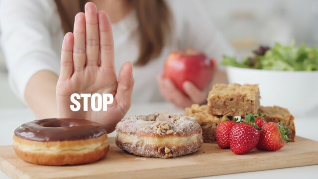 Woman making a stop gesture to junk food and choosing a healthy apple