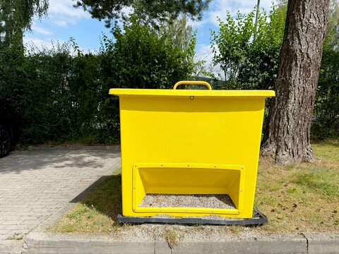 Yellow grit bin for storing road salt and de-icing materials outdoors in winter.
