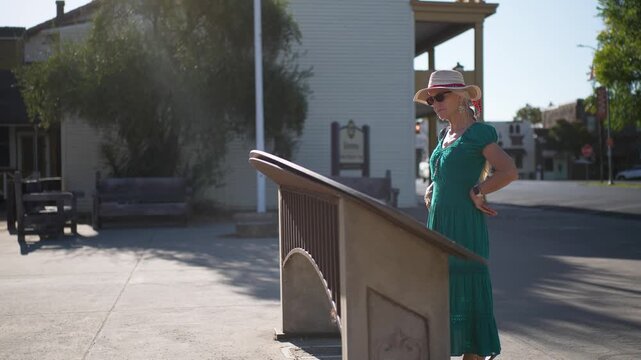 A senior woman enjoys a lovely morning as she walks through Casa Grande in Sonoma, reading about its history after sunrise.