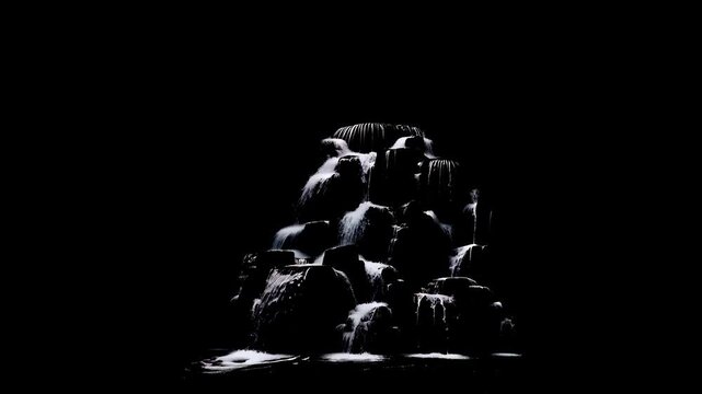 Small rock fountain with flowing water isolated on black background. Waterfall feature cascades down dark stone structure. Minimalist nature design for decoration.