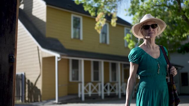 Smiling senior woman walks through historic Casa Grande in Sonoma reading about General Vallejos history on a lovely morning.