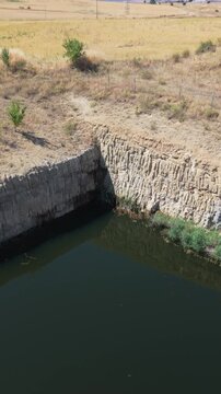 Abandoned open-pit mine filled with water and surrounded by arid land in a rural area of Spain, showing the environmental impact of extractive industries on the landscape