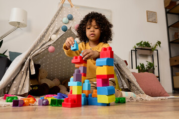 Creative playtime for a joyful boy building colorful blocks at home © LIGHTFIELD STUDIOS