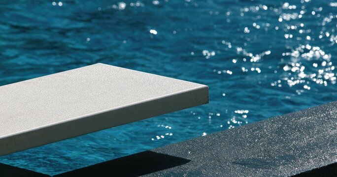 A bright, close-up shot of a diving board over a sparkling blue pool