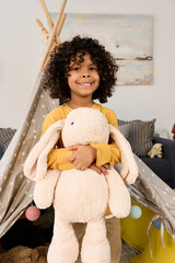 Joyful moments of a black boy playing with his stuffed bunny at home © LIGHTFIELD STUDIOS