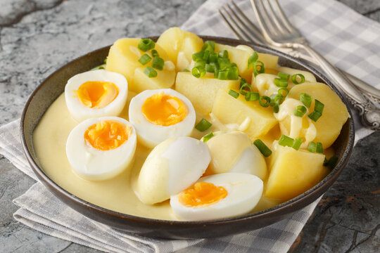 Senfeier hard boiled eggs in creamy mustard sauce with potato close-up in a plate on the table. Horizontal