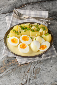 Senfeier or mustard eggs is a traditional German egg dish with a creamy mustard sauce and hard-boiled eggs close-up in a plate on the table. Vertical