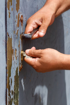 Hands unlock old, weathered metal door handle