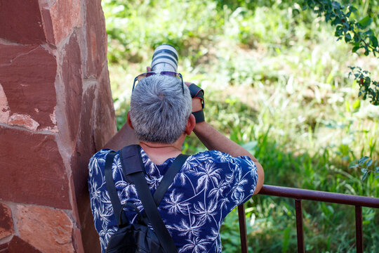 Man shoots photo from stone wall