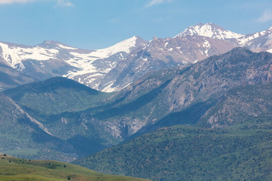 Snow-capped peaks rise above layered green valleys