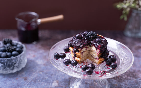 Blueberry Pancakes with Berry Compote, Stack of fluffy pancakes topped with blueberry compote and fresh berries served on a glass cake stand
