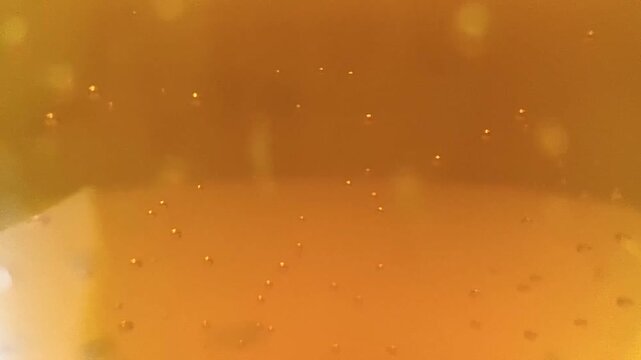 Macro close up of orange liquid with tiny rising gas bubbles sparkling carbonated soda drink effervescent orange juice beverage texture background video clip stock footage