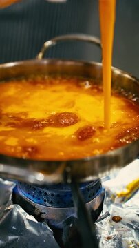Pouring Liquid Egg Mix over Frying Spicy Turkish Sausage in Pan