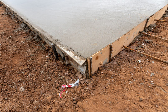 Perspective close-up of freshly leveled concrete slab with wooden formwork and dowel rebar bars