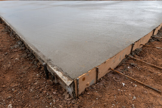 Perspective close-up of freshly leveled concrete slab with wooden formwork and dowel rebar bars